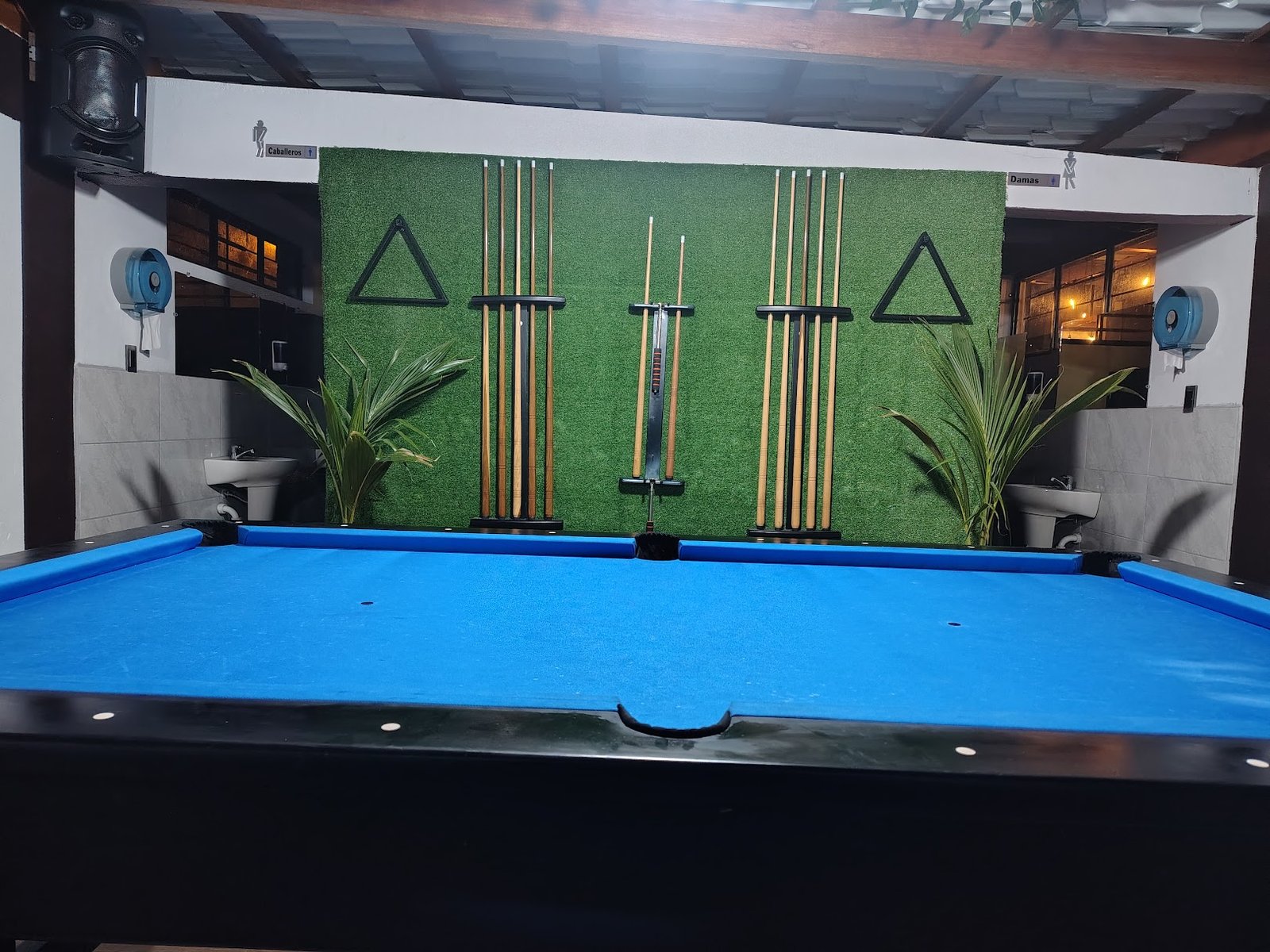 Mesa de billar y tacos en la pared